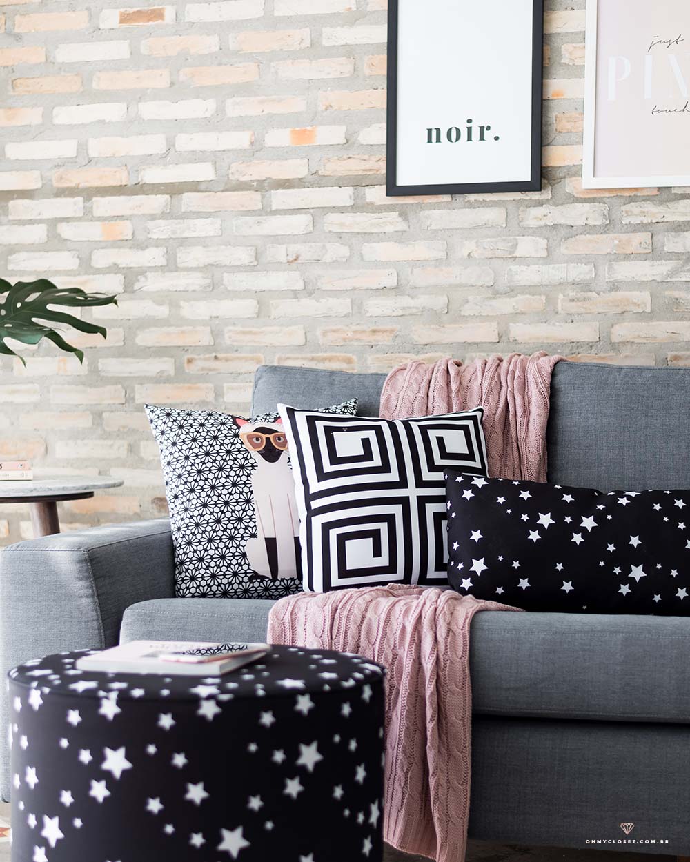 Sala de estar com sofá cinza e toque de preto e rosé. Itens de decorações da marca Nita Faco.